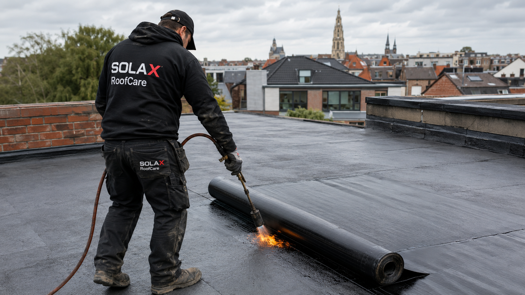 Technicien SOLAX RoofCare posant une membrane bitumineuse sur une toiture plate en Belgique